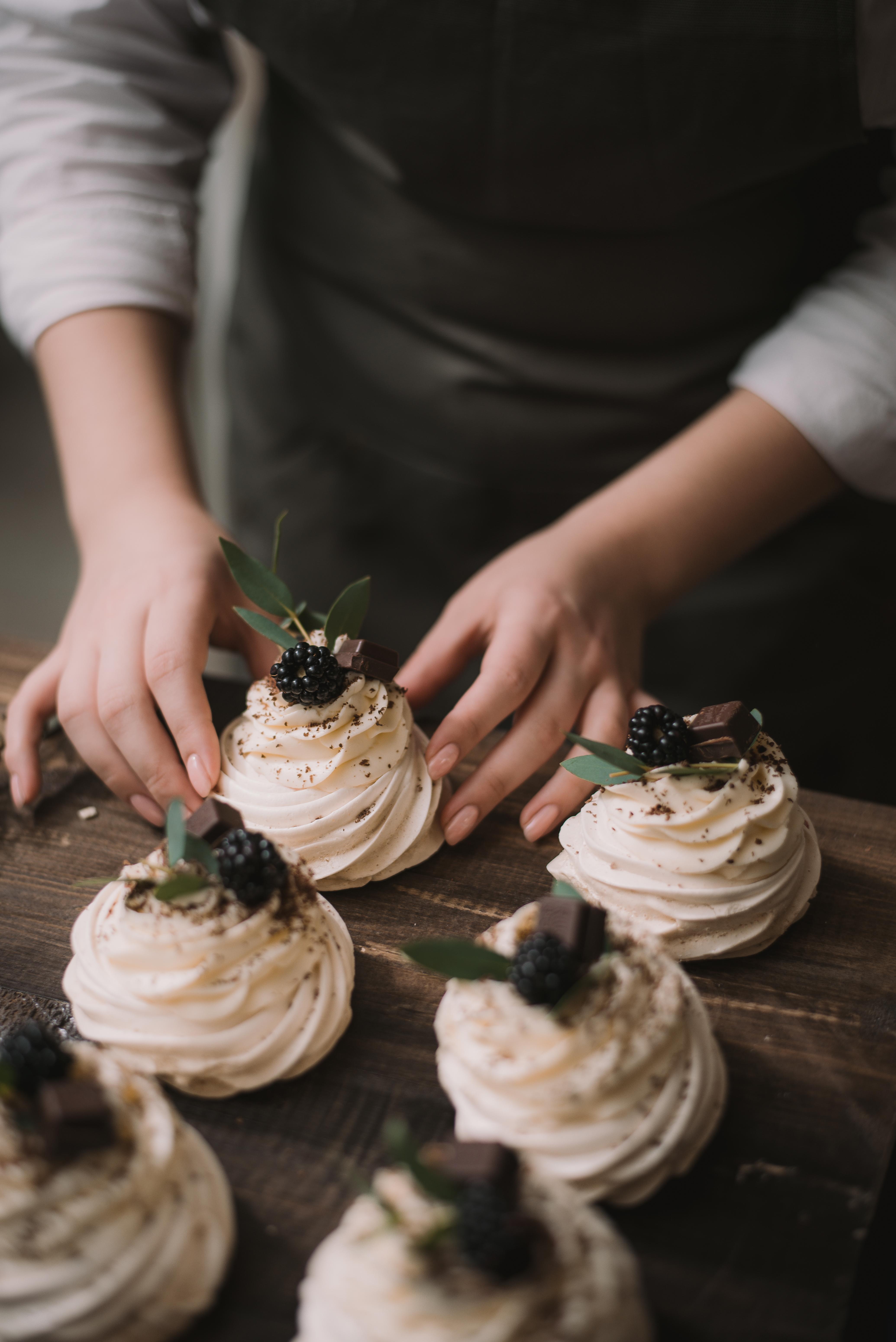 Confectioner creates a wedding dessert. Girl collects sweet dessert from meringue, chocolate and berries