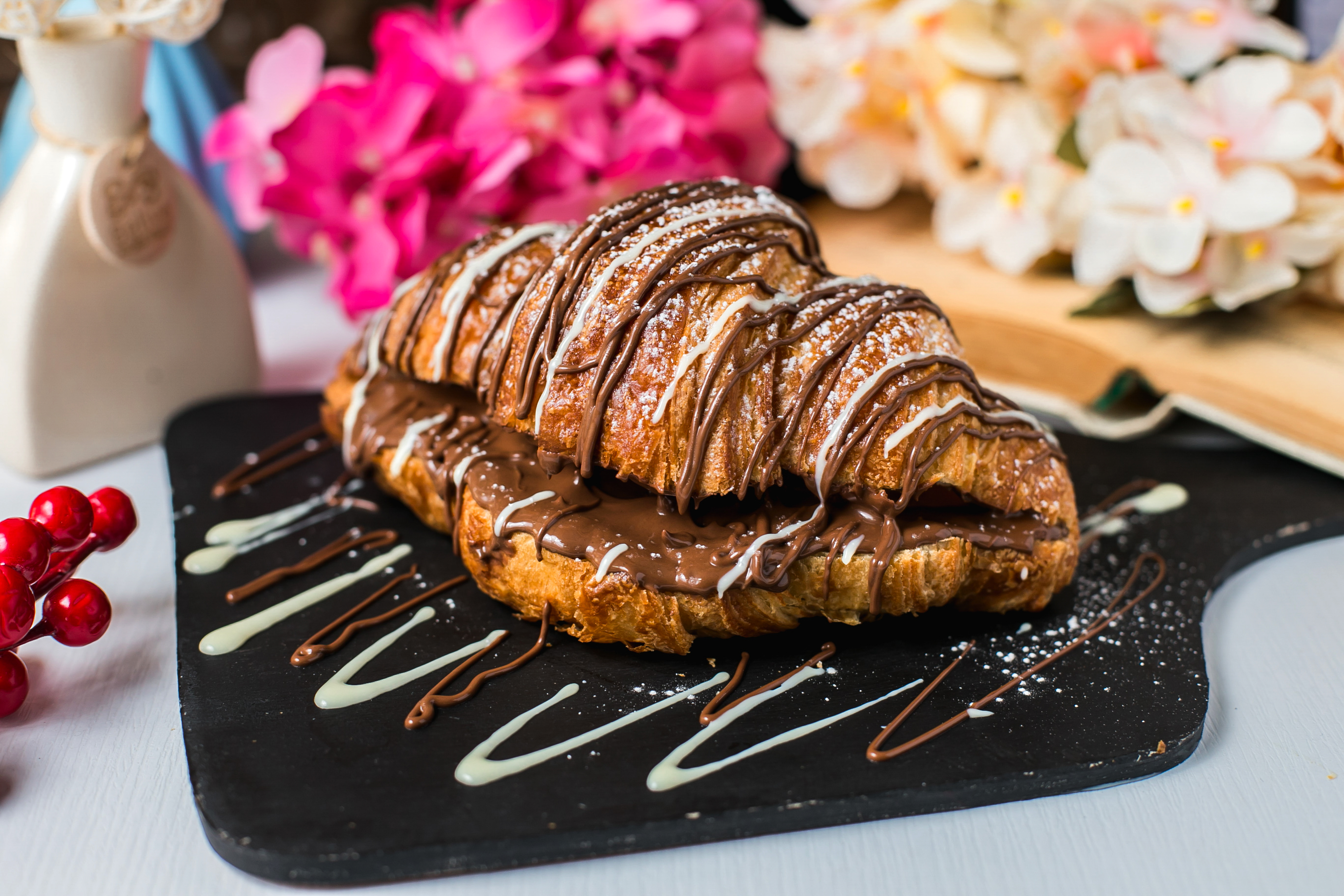 side view of croissant decorated with chocolate on a wooden board side view of croissant decorated with chocolate on a wooden board